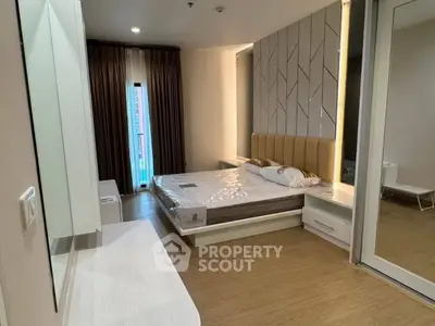 Modern bedroom with stylish decor and large window offering natural light.
