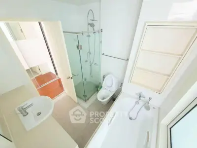 Modern bathroom with glass shower and bathtub in bright apartment