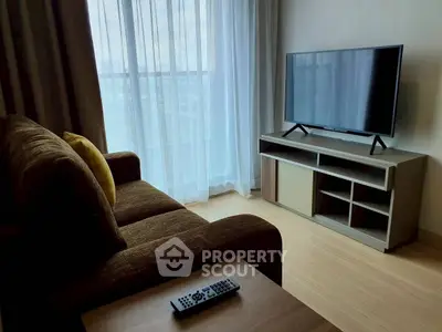 Modern living room with cozy sofa and flat-screen TV, featuring floor-to-ceiling windows for natural light.