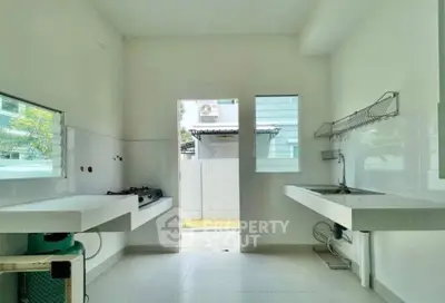 Spacious kitchen with open layout and modern gas stove, featuring ample natural light and sleek design.
