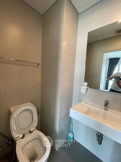 Modern bathroom with sleek fixtures and large mirror in contemporary apartment.