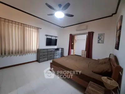 Spacious bedroom with modern furnishings and ample natural light, featuring a ceiling fan and wall-mounted TV.