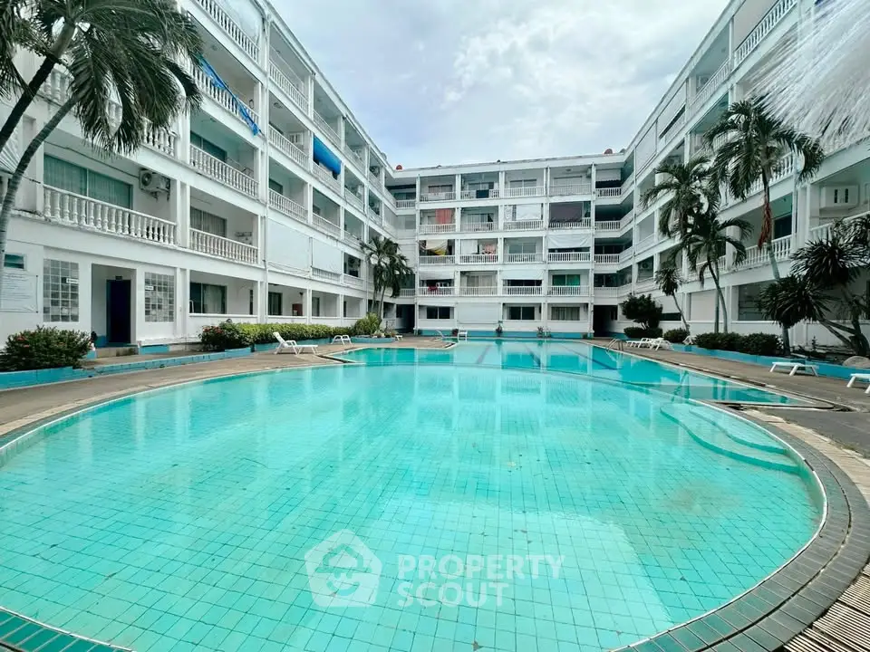 Spacious apartment complex with inviting pool and lush palm trees, perfect for relaxation and leisure.