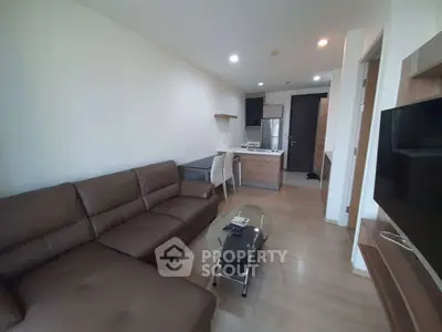 Modern living room with brown leather sofa and open kitchen layout