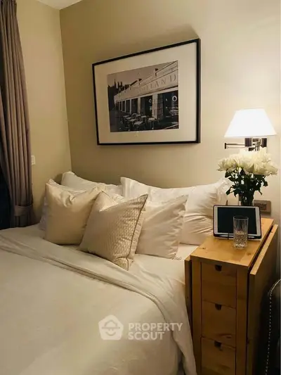 Cozy bedroom with elegant decor and soft lighting, featuring a stylish bedside table and framed artwork.