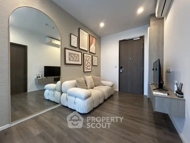 Modern living room with stylish decor and large mirror, featuring a cozy white sofa and wall-mounted TV.