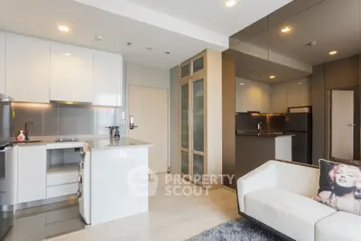 Modern open-layout kitchen with sleek cabinetry and cozy living area in a stylish apartment.