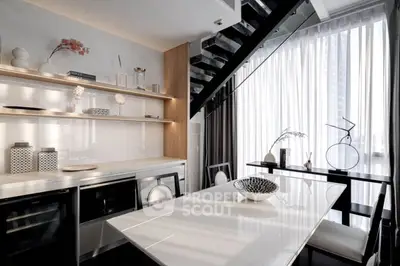 Modern kitchen with sleek design, open layout, and elegant dining area under staircase.
