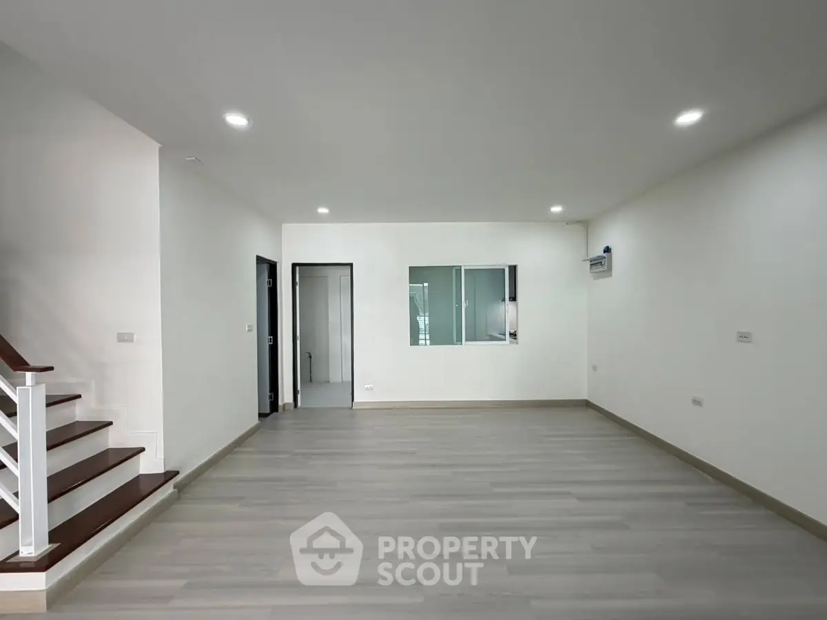 Spacious modern living room with sleek flooring and recessed lighting, perfect for contemporary living.