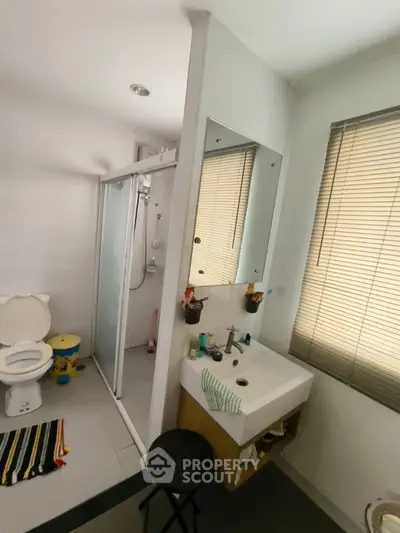 Modern bathroom with shower and sink, featuring sleek design and natural light.