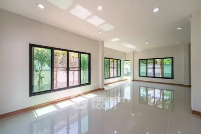 Spacious and bright living room with large windows and glossy tiled floors, perfect for modern living.