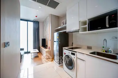 Modern apartment with open kitchen and living area, featuring sleek appliances and stylish decor.