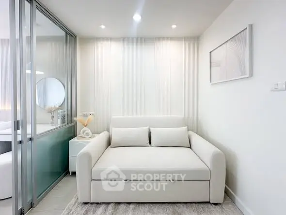 Modern living room with sleek white sofa and glass partition in stylish apartment.