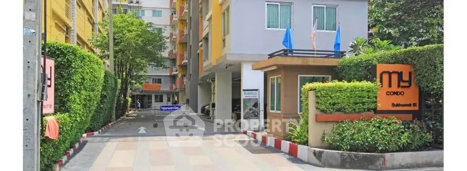 Modern condo entrance with lush greenery and secure gated access in vibrant city location.