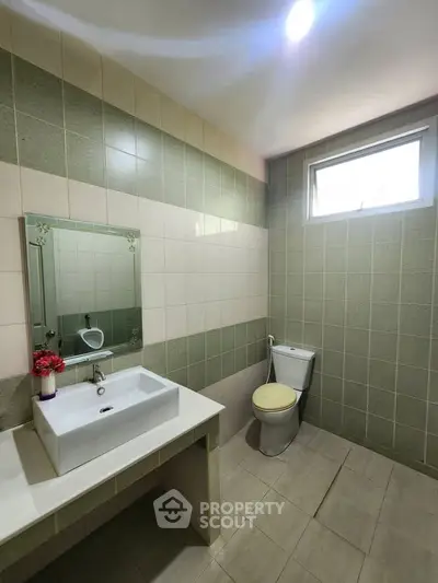 Spacious bathroom with modern sink and toilet, featuring stylish tile design and natural light.