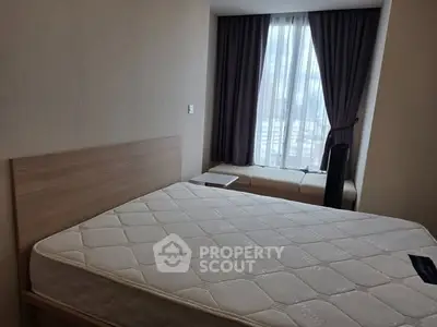 Cozy bedroom with large window and modern decor in urban apartment.