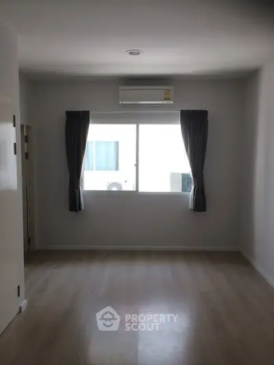 Spacious empty room with large window and air conditioning, perfect for customization.