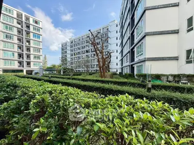 Modern apartment buildings with lush green garden and clear blue sky
