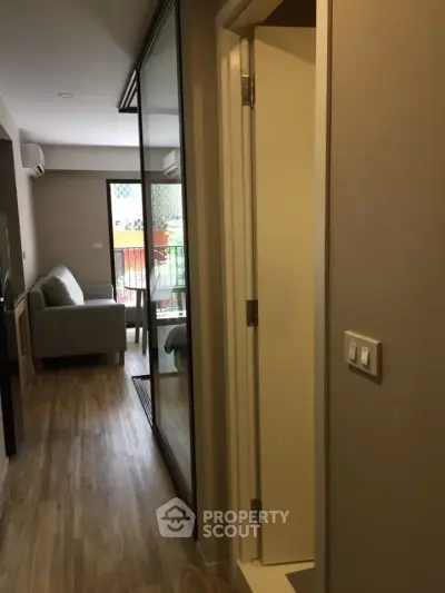 Modern apartment hallway leading to a cozy living room with balcony access.