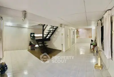 Spacious open-plan living area with staircase and tiled flooring, ideal for modern living.
