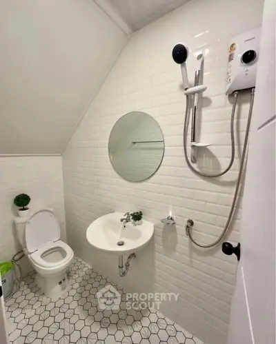 Modern bathroom with white tiles, round mirror, and compact shower setup.