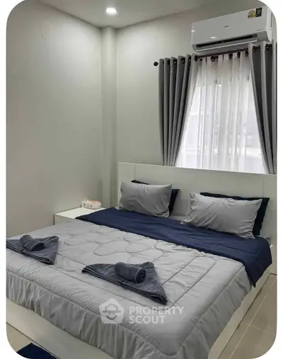 Modern bedroom with stylish decor and air conditioning, featuring a cozy bed and elegant curtains.