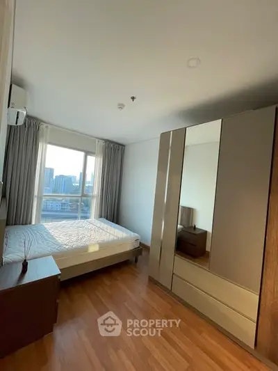 Spacious bedroom with city view, wooden flooring, and modern wardrobe in a high-rise apartment.