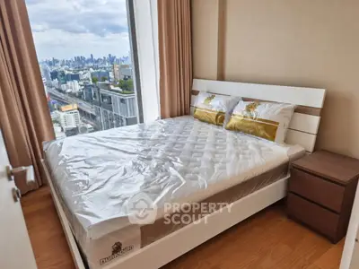 Modern bedroom with city view in high-rise apartment, featuring a comfortable bed and wooden flooring.