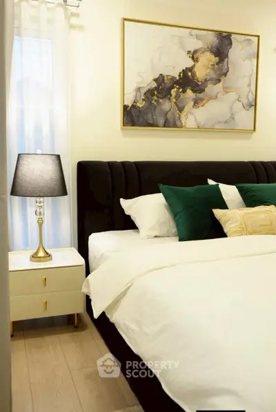 Elegant bedroom with plush bed, stylish artwork, and chic bedside lamp