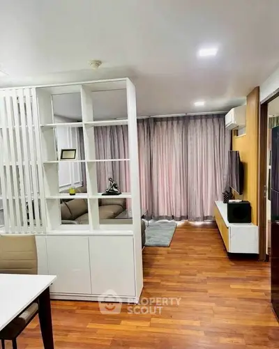 Modern living room with stylish decor, wooden flooring, and elegant shelving unit.