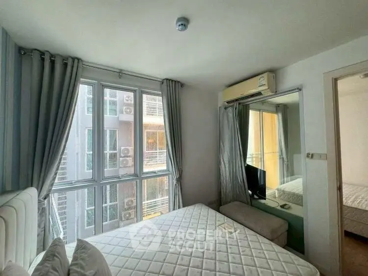Bright bedroom with large windows and modern air conditioning unit in a high-rise apartment.