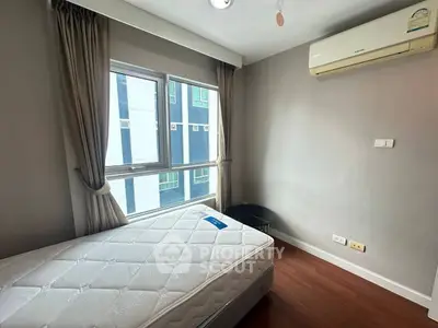 Cozy bedroom with large window and air conditioning in modern apartment.