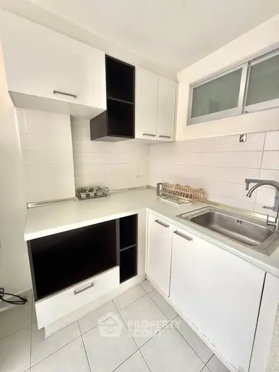 Modern kitchen with sleek white cabinetry and stainless steel sink, perfect for urban living.
