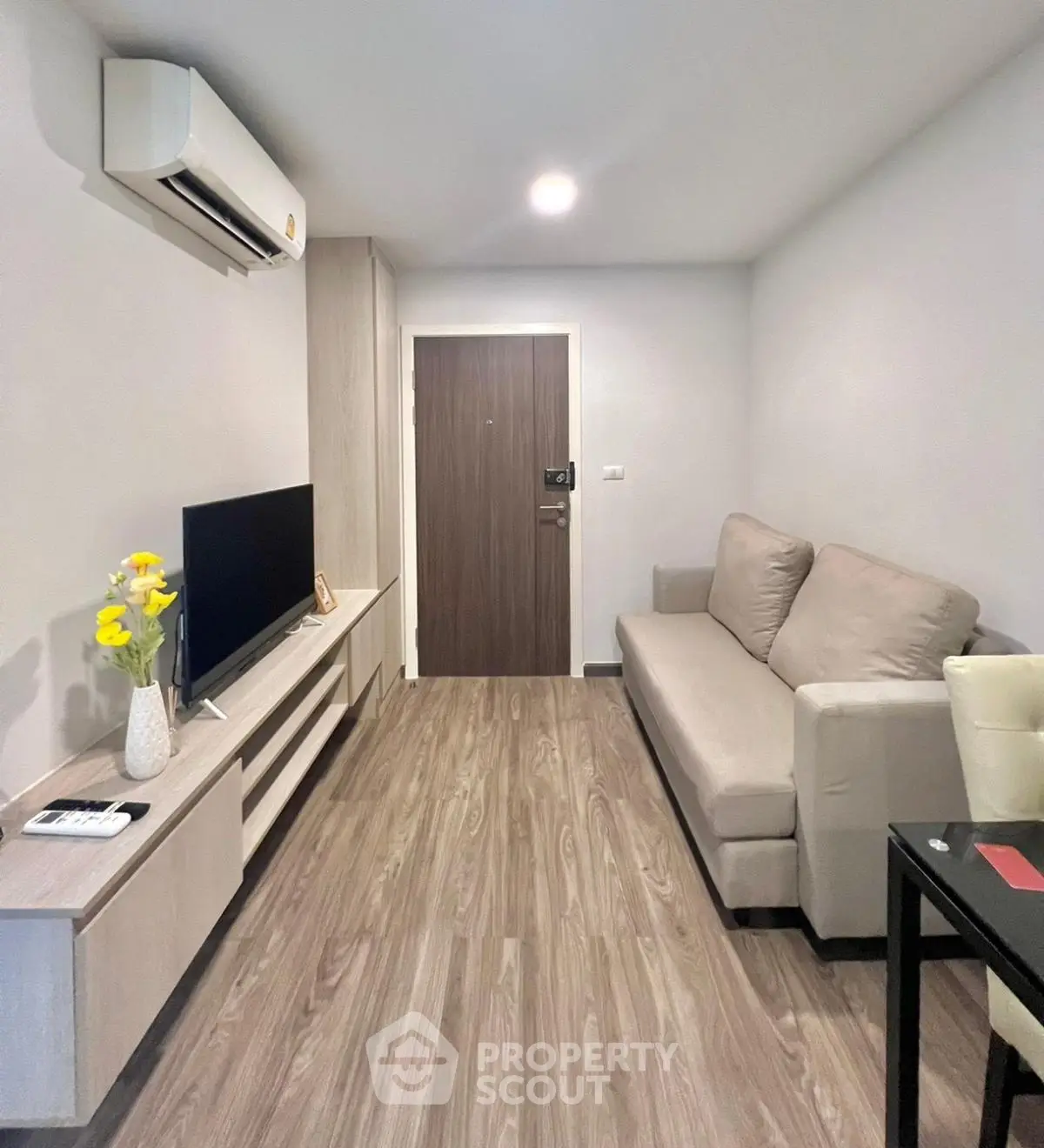 Modern living room with sleek design and cozy sofa, featuring a flat-screen TV and air conditioning.