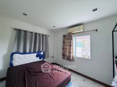 Cozy bedroom with modern decor and air conditioning, featuring a comfortable bed and large windows for natural light.