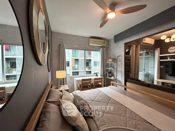 Modern bedroom with stylish decor and large windows offering natural light and urban views.