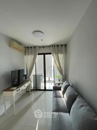 Modern living room with sleek furniture and natural light, featuring a cozy sofa and entertainment setup.