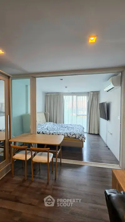 Modern studio apartment with glass partition, cozy bedroom, and stylish dining area.