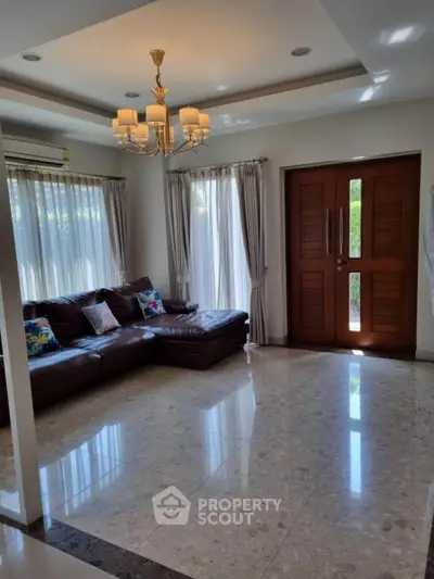Spacious living room with elegant chandelier and large windows for natural light.