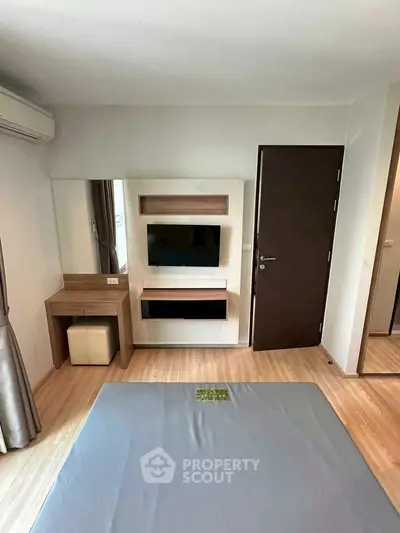 Modern bedroom with sleek wooden flooring and built-in TV unit, featuring a stylish vanity corner.