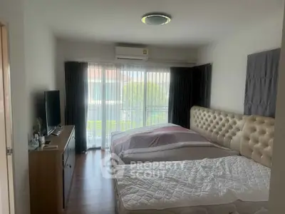 Cozy bedroom with modern decor, featuring a large bed, TV, and natural light from a window.