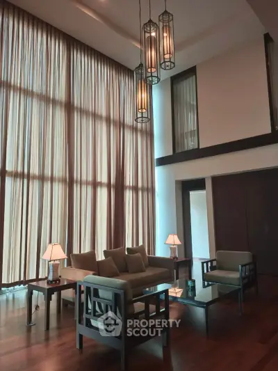 Luxurious high-ceiling living room with elegant lighting and floor-to-ceiling windows.