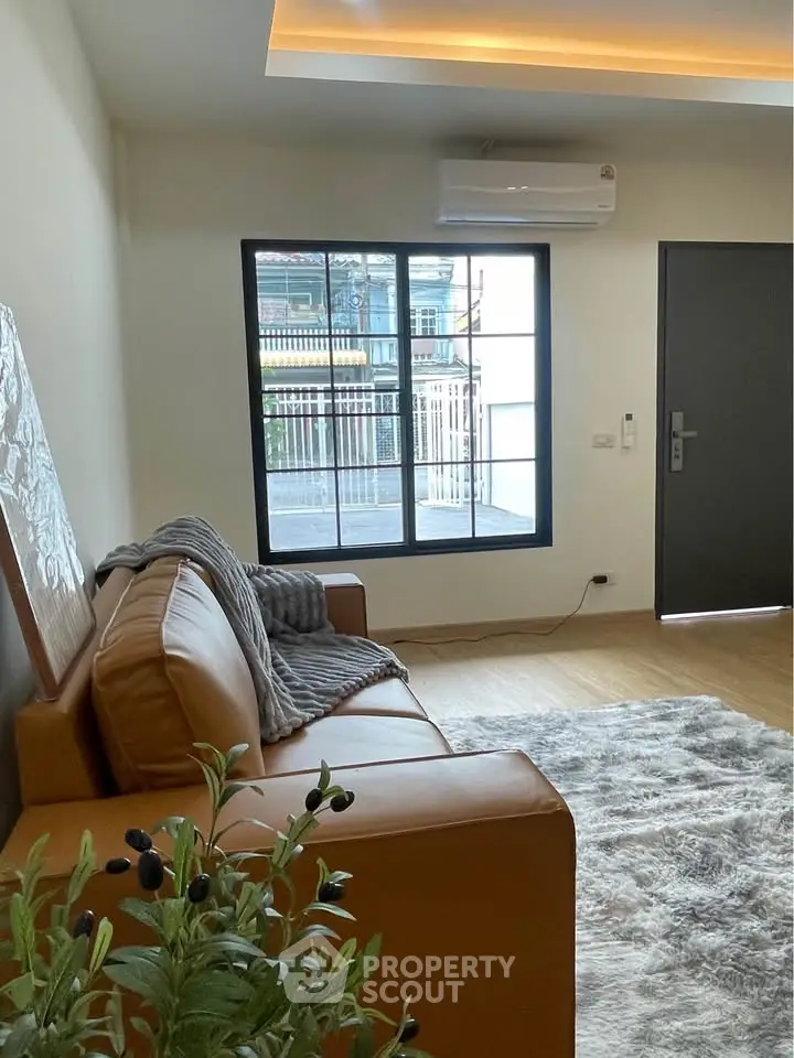 Modern living room with cozy leather sofa and large window view.