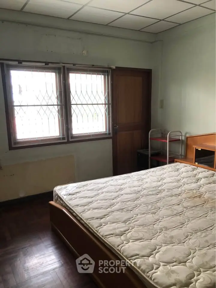 Cozy bedroom with natural light and wooden flooring, ideal for restful nights.