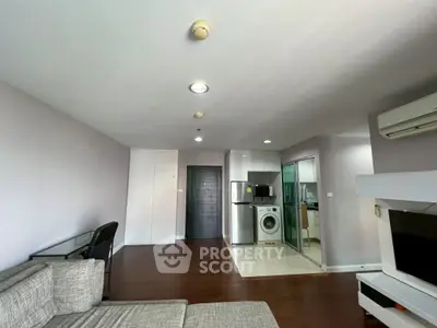 Modern living room with open kitchen and washing machine, featuring sleek design and hardwood floors.