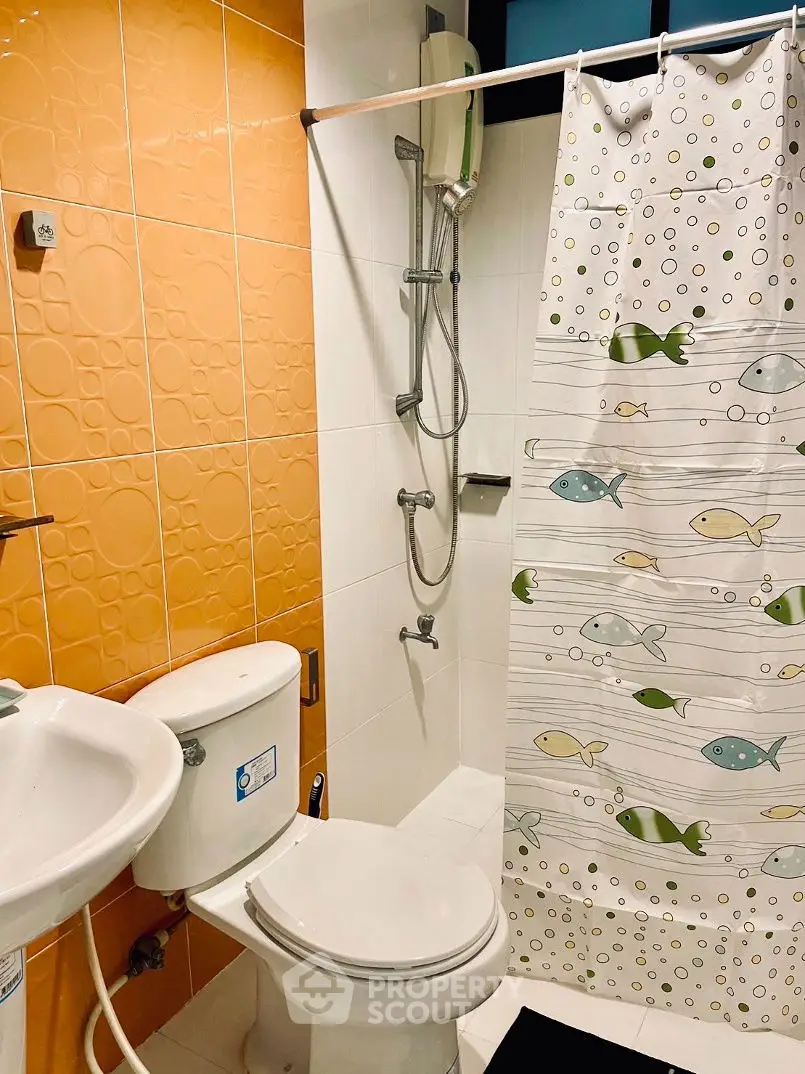 Charming bathroom with vibrant orange tiles and playful fish-themed shower curtain.