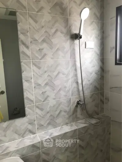 Modern bathroom with stylish herringbone tiles and sleek showerhead