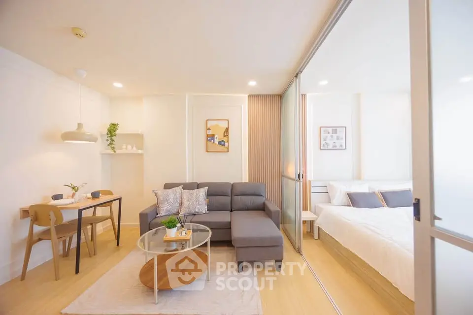 Modern open-plan living room with cozy sofa and stylish dining area adjacent to a bright bedroom.