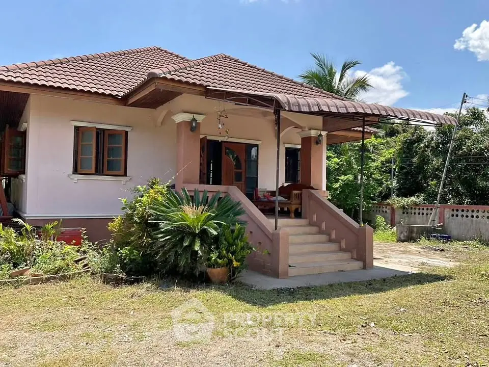 Charming single-story house with a tiled roof and lush garden, perfect for family living.