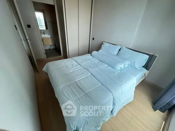 Cozy bedroom with blue bedding and ensuite bathroom in modern apartment